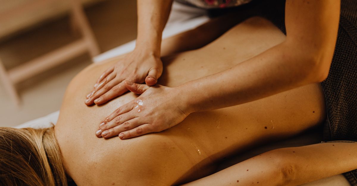 A therapist's hands applying warm oil during a traditional Balinese back massage