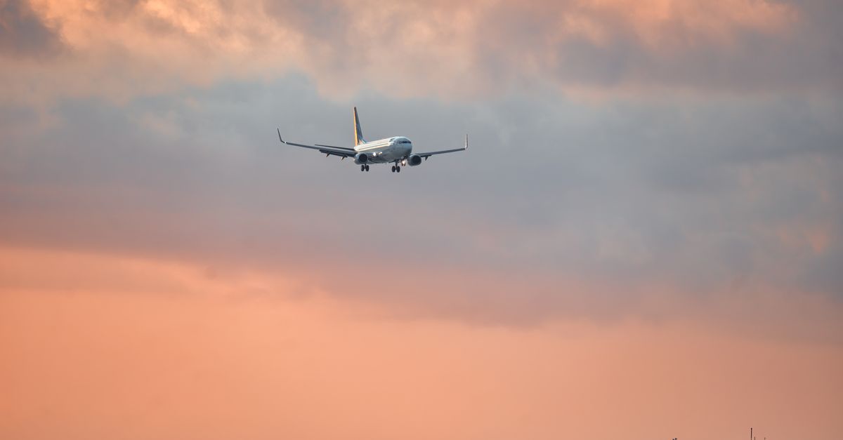 An aeroplane approaching to land against a vibrant Bali sunset sky