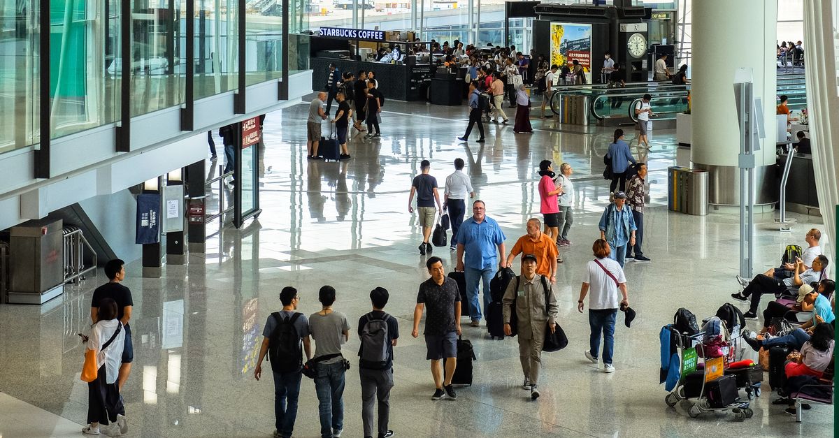 Passengers walking through a busy airport terminal, the kind of departure hall you pass through on a Bali visa run