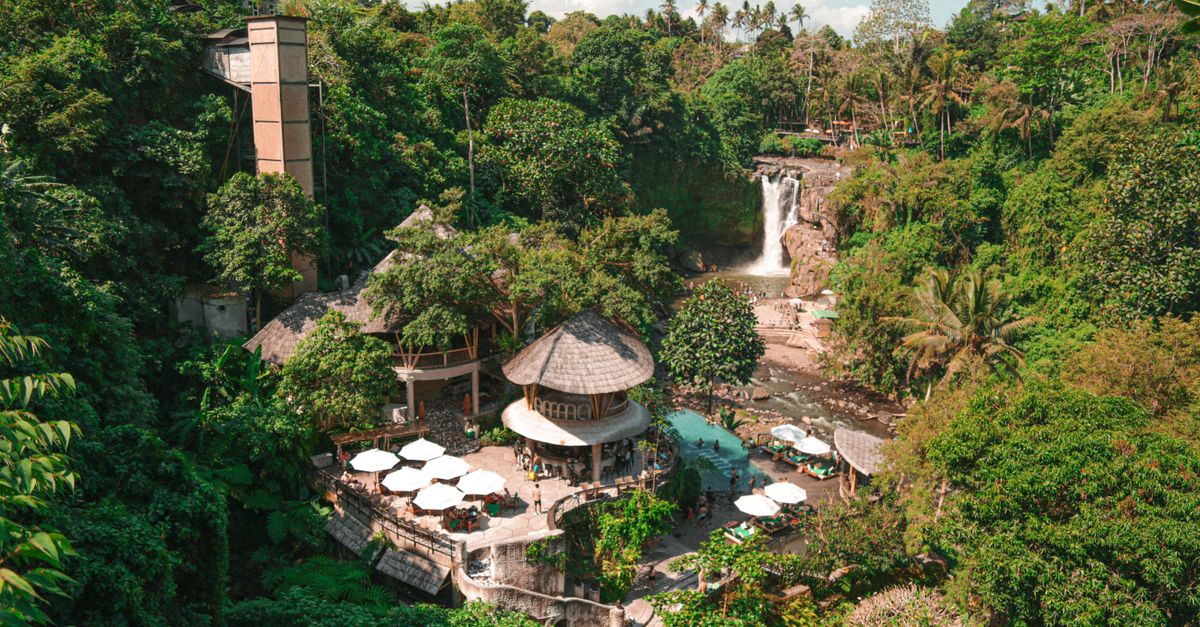 A serene tropical resort nestled in a lush forest in Bali, featuring a waterfall.