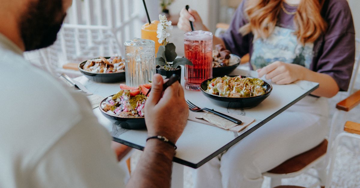 Friends sharing colourful smoothie bowls and healthy brunch plates at a bright, modern Bali cafe.