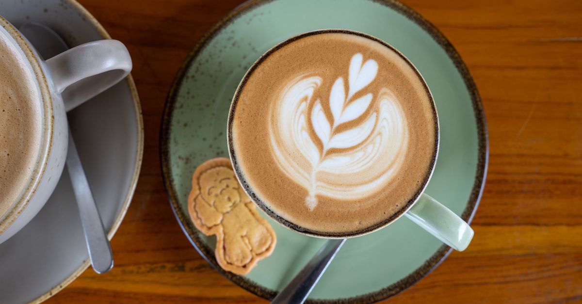 Beautiful latte art on coffee served in Bali, Indonesia with a cute cookie on the side.