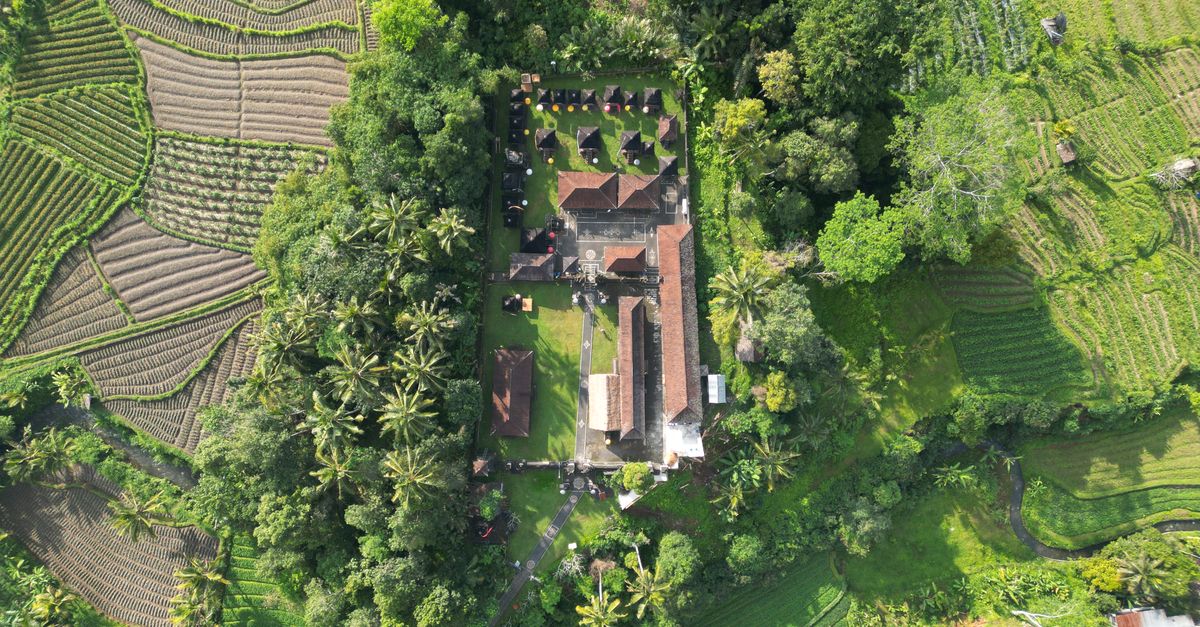 Aerial view of a Balinese temple nestled among green rice terraces
