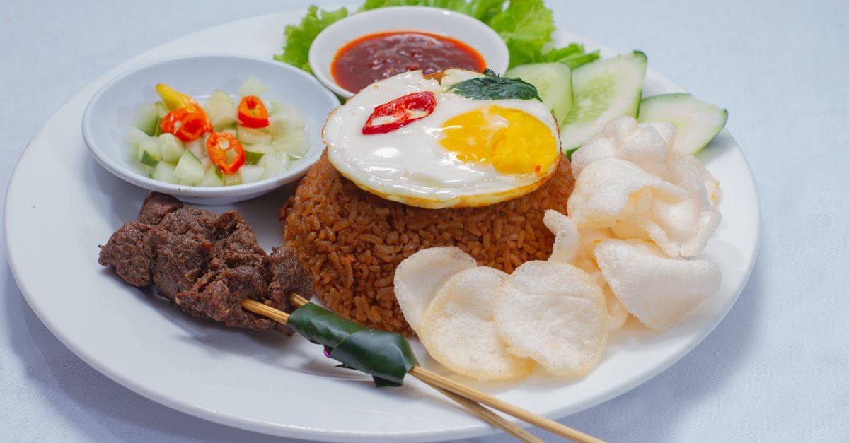 A plate of Balinese nasi goreng with a fried egg, satay and crackers