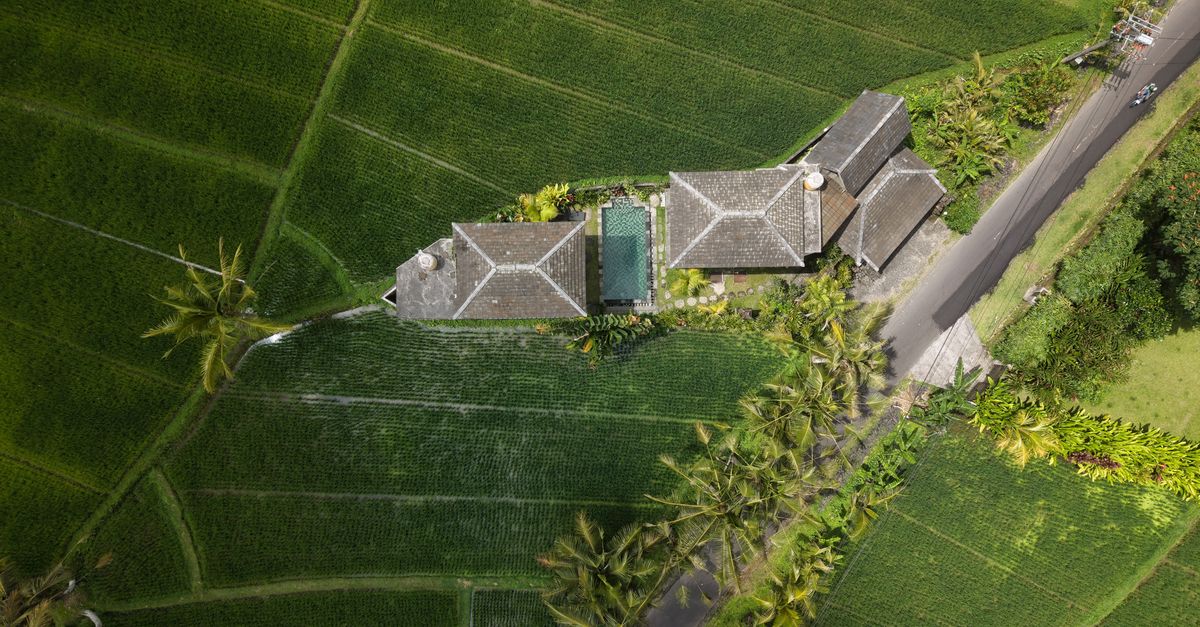 Aerial view of a traditional villa surrounded by lush rice fields in Umalas, Bali